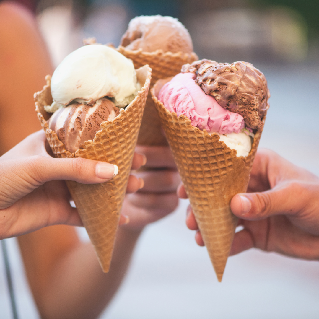 Three people holding ice cream cones together in a "cheers" arrangement